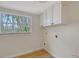 A bright laundry room with white cabinets, a window, and wood floors at 1203 Lyric Ln, Sarasota, FL 34242