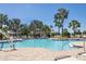 Inviting community pool surrounded by lounge chairs and tropical palm trees at 15508 High Bell Pl, Bradenton, FL 34212