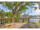 Wooden deck overlooking a waterfront canal and boat lift shaded by a mature tree at 2002 8Th W St, Palmetto, FL 34221