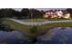 Picturesque property featuring a white-fenced home, pond with lily pads, and circular driveway at dusk at 20504 65Th E Ave, Bradenton, FL 34211