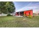 Exterior view of red barn on well-maintained lawn with mature trees and equipment storage at 20504 65Th E Ave, Bradenton, FL 34211