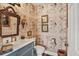 Charming powder room boasts decorative wallpaper, toilet, custom vanity and vintage-style mirror at 20504 65Th E Ave, Bradenton, FL 34211