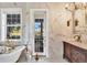 Bright, luxurious bathroom with marble walls, soaking tub, and large windows overlooking the property at 20504 65Th E Ave, Bradenton, FL 34211