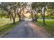Scenic view of a long driveway leading to a gated entrance, framed by mature trees and greenery at 20504 65Th E Ave, Bradenton, FL 34211