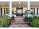 Charming front entrance with brick steps, black door, lush plants, and lantern sconces at 20504 65Th E Ave, Bradenton, FL 34211