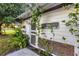 Exterior side view of the quaint, white potting shed featuring a hanging sign and vine-covered wall at 20504 65Th E Ave, Bradenton, FL 34211
