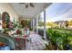 View of outdoor screened porch with wicker furniture and chandelier, with a gazebo and large lawn beyond at 20504 65Th E Ave, Bradenton, FL 34211