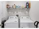 Functional laundry room with a white washer and dryer and storage shelving above at 2105 Grand Flora Trl, Bradenton, FL 34208