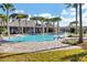 Community swimming pool surrounded by towering palm trees with a clubhouse and seating area at 2105 Grand Flora Trl, Bradenton, FL 34208
