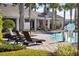 A community pool is showcased, lined with lounge chairs, palm trees and a covered recreational building at 2105 Grand Flora Trl, Bradenton, FL 34208