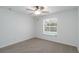 This is a bright bedroom featuring a ceiling fan, neutral carpet, and a large window offering natural light at 2199 Palm Ct, North Port, FL 34287