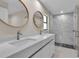 Elegant bathroom featuring a double vanity with round mirrors and a modern walk-in shower at 23367 Mayville Ave, Punta Gorda, FL 33980