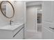Bright bathroom showcasing a modern vanity, round mirror, and doorway view to kitchen appliances at 23367 Mayville Ave, Punta Gorda, FL 33980