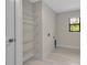 Well-lit laundry room with white wood-look tile, wire shelves, and a window at 23367 Mayville Ave, Punta Gorda, FL 33980