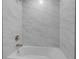 Modern bathroom featuring a white tub with marble-style tile surround and sleek fixtures at 23367 Mayville Ave, Punta Gorda, FL 33980