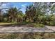 Expansive grassy property area with tall palm trees and a winding gravel driveway at 2740 Orchid Oaks Dr # 304, Sarasota, FL 34239
