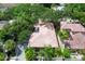Aerial view of a home with a red tile roof, surrounded by lush greenery and mature trees in a desirable neighborhood at 3837 Camino Real, Sarasota, FL 34239
