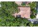 Aerial view of a single-Gathering home with a red tile roof, lush trees, and screened-in pool area at 3837 Camino Real, Sarasota, FL 34239