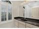 Bright bathroom with a black vanity, large mirror, and window with plantation shutters at 3837 Camino Real, Sarasota, FL 34239