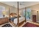 Bedroom featuring a four-poster bed, natural light, and access to outdoor patio at 3837 Camino Real, Sarasota, FL 34239