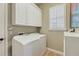 Bright laundry room with white cabinets, appliances, and a large window at 3837 Camino Real, Sarasota, FL 34239