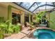 Private, screened-in pool and patio area with seating and mature tropical landscaping at 3837 Camino Real, Sarasota, FL 34239