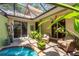 Relaxing, screened-in pool and patio area surrounded by lush greenery and comfortable seating at 3837 Camino Real, Sarasota, FL 34239