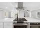 Modern kitchen with a stainless steel range hood, sleek countertops, and an adjacent living space at 3975 Coleridge Pl, Sarasota, FL 34241
