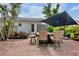 Outdoor brick patio area with dining table, lots of foliage, and an umbrella at 404 Bayshore Rd, Nokomis, FL 34275