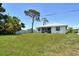 Backyard view of a home with a lawn, white fence, and large shade tree at 4484 Tortoise Rd, Venice, FL 34293