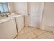 Efficient laundry room with a washer, dryer, tiled floor, and a nearby door at 4484 Tortoise Rd, Venice, FL 34293