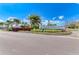Landscaped roundabout entrance with a 'Canoe Creek' community sign surrounded by vibrant flowers and palm trees at 4625 Canoe Creek Ave, Parrish, FL 34219