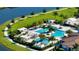 Aerial view of community pool with cabanas, palm trees, and lush landscaping near a lake and walking path at 5187 Barnett Cir, Lakewood Ranch, FL 34211