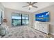Comfortable bedroom with large window views, ceiling fan, and dresser with mounted TV at 5187 Barnett Cir, Lakewood Ranch, FL 34211
