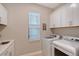 Bright laundry room with washer, dryer, sink, white cabinets, and natural light at 5187 Barnett Cir, Lakewood Ranch, FL 34211