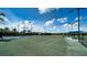 Well-maintained tennis court with green surface, lighting, and blue canopy for shade at 5187 Barnett Cir, Lakewood Ranch, FL 34211