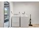 Bright laundry room with washer, dryer, vacuum, and doorway to the outside at 5192 Cedar Hammock Ln, Sarasota, FL 34232