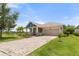 Beautiful home featuring a brick driveway, two-car garage, lush landscaping, and lake view at 5240 Bentgrass Way, Bradenton, FL 34211