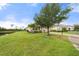 Well-manicured front yard featuring lush lawn, mature tree, and a glimpse of the home's facade with elegant columns at 5240 Bentgrass Way, Bradenton, FL 34211
