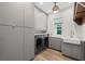 Well-lit laundry room featuring modern gray cabinets, washer, dryer, and sink at 5240 Bentgrass Way, Bradenton, FL 34211