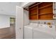 This laundry room includes a washer, dryer, storage shelves, and easy access to sunroom at 5356 Royal Palm Ave # 5356, Sarasota, FL 34234