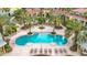 Aerial view of a resort style pool with lounge chairs and palm trees at Las Palmas at 5459 Bentgrass Dr # 2-116, Sarasota, FL 34235
