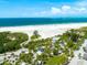 Aerial view of a sandy beach with clear blue waters, greenery, and a building for visitors at 5600 Beach Way Dr # 201, Sarasota, FL 34242