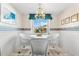 Cozy dining area with a glass table, white wicker chairs, and natural light filtering through the window at 5600 Beach Way Dr # 201, Sarasota, FL 34242
