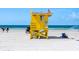 A bright yellow lifeguard tower stands watch over the white sands and calm, blue waters of the beach at 5600 Beach Way Dr # 201, Sarasota, FL 34242