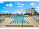 Community swimming pool with lounge chairs and umbrellas overlooking bay at 5600 Beach Way Dr # 201, Sarasota, FL 34242