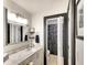 Bathroom with granite countertop, white cabinets, black trim, shower, and framed mirror at 6024 28Th W St, Bradenton, FL 34207