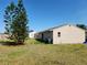 Large backyard with grassy lawn, mature trees, and a neighboring house beyond the property line at 6405 Myrtlewood Rd, North Port, FL 34287