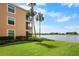 Back of building with lush lawn extending to the waterfront, lined with palm trees at 6515 Grand Estuary Trl # 208, Bradenton, FL 34212