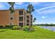 Multi-story residential building with well-kept lawn, tropical trees, and lake view at 6515 Grand Estuary Trl # 208, Bradenton, FL 34212
